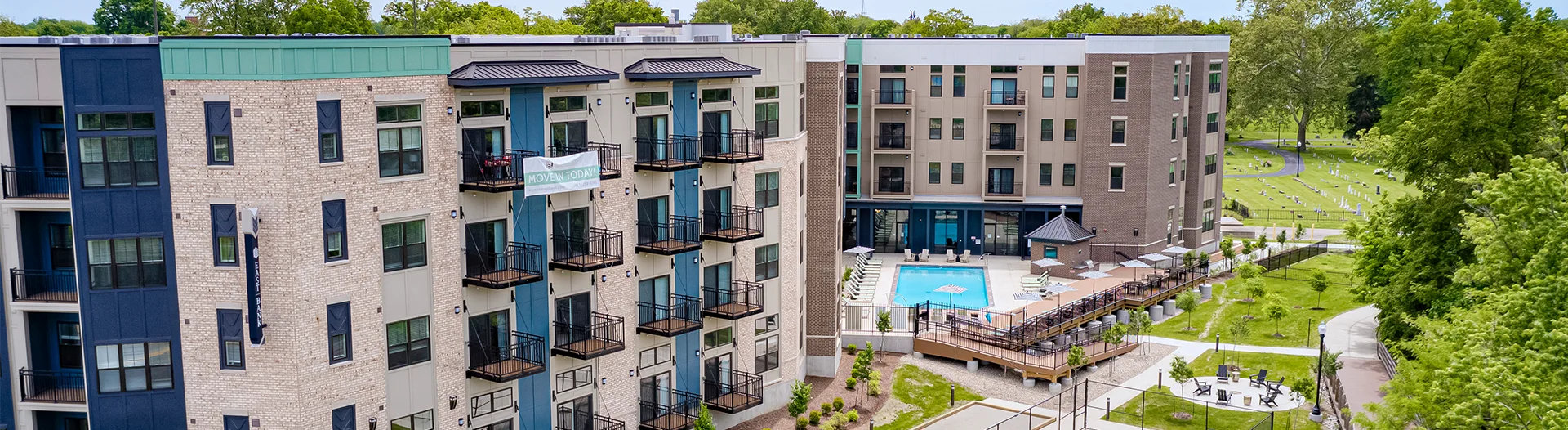 Wide aerial view of East Bank Apartments buildings and outdoor amenities with no lights on
