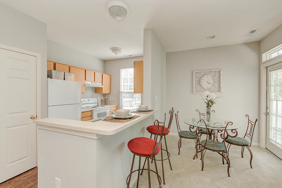 A kitchen and dining room with uncovered windows in an Ashley Place Apartments apartment